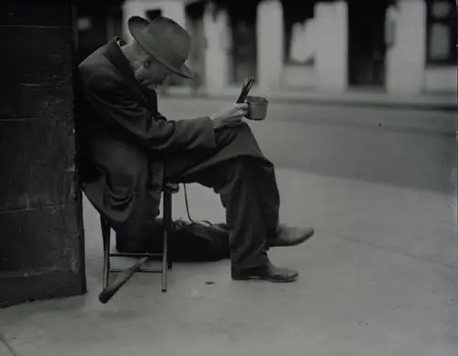 poor man sitting hunched over on a sidewalk