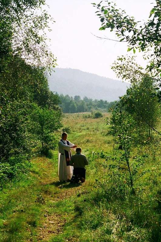 priest blessing a scout outdoors