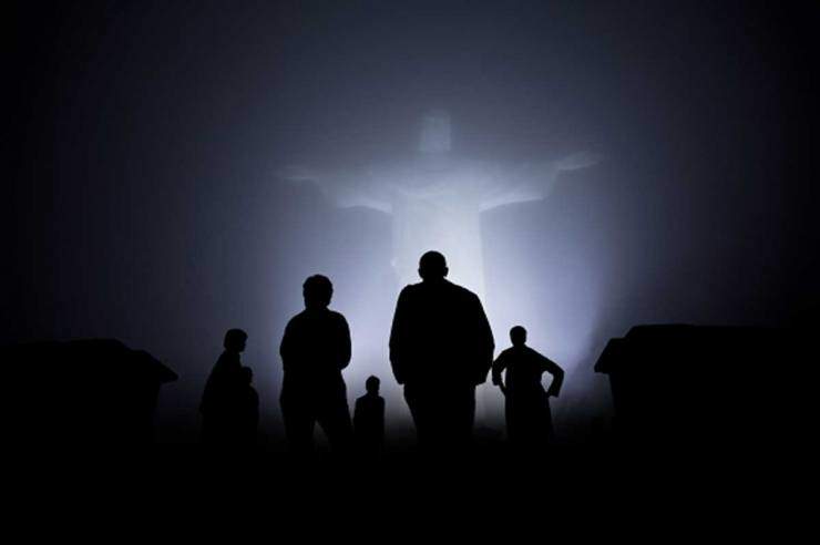 Silhouette of people looking at a statue of risen Christ