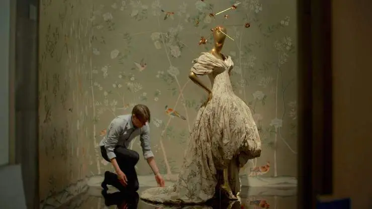 Man adjusting the train on a mannequin's dress