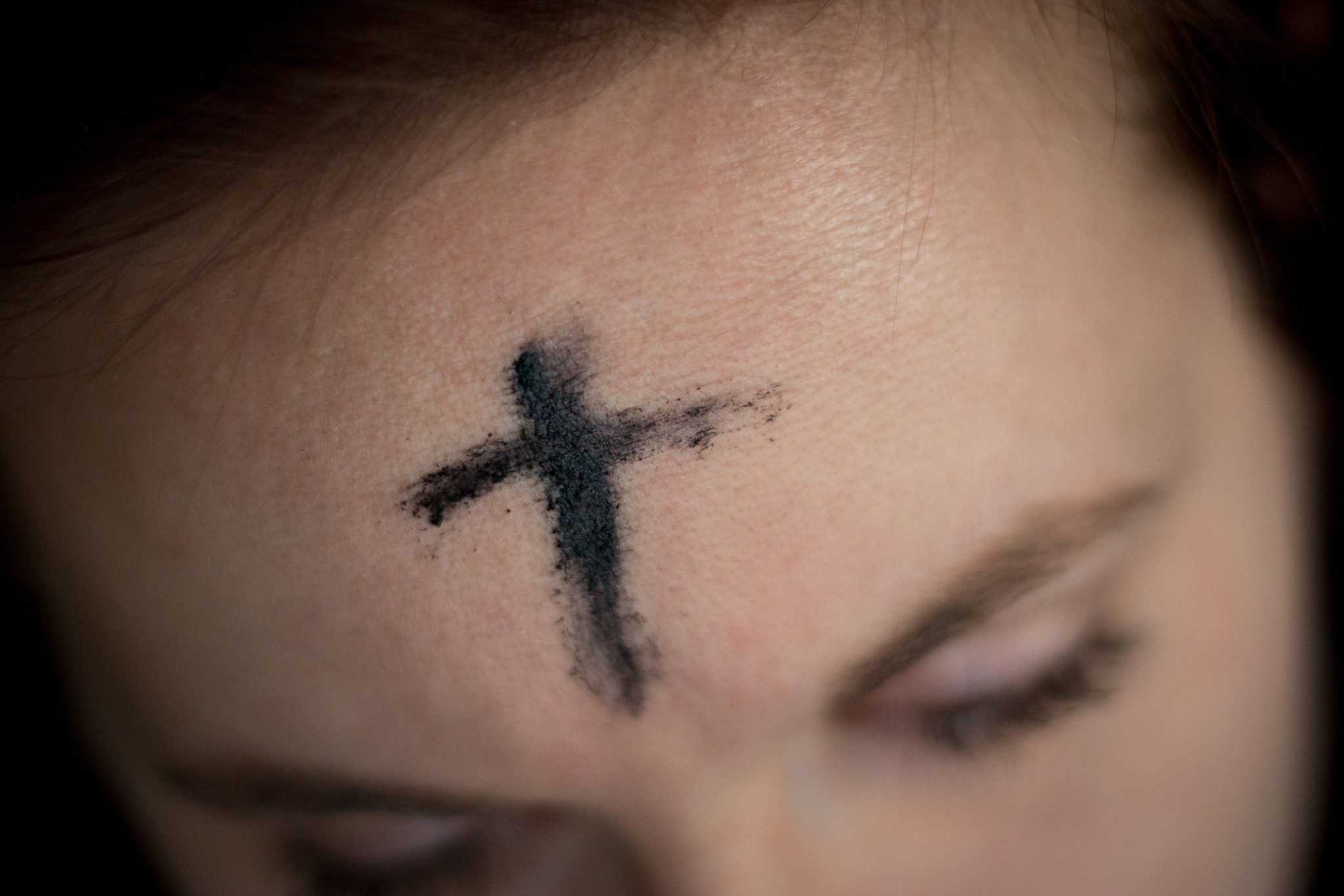 Ashes in the shape of a cross on a person's forehead