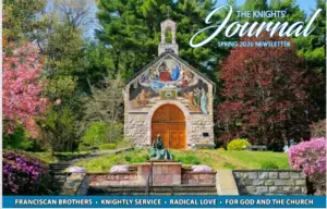A small stone chapel with a colorful mural above its wooden door sits surrounded by lush green trees, pink blossoming flowers, and neatly trimmed bushes. A bronze statue graces the steps in front, featured in the Knights Journal Spring 2026 Newsletter.